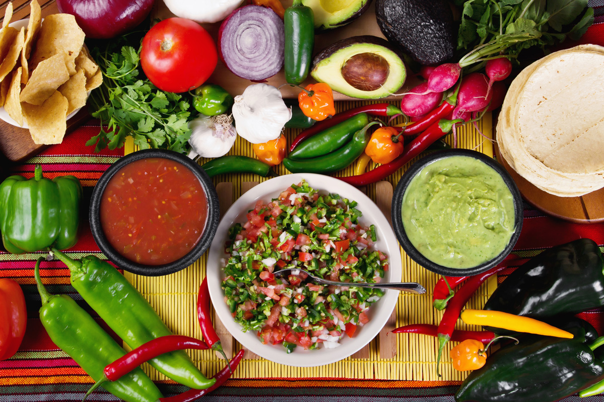 A table with various Hispanic food products, including salsa and guacamole.